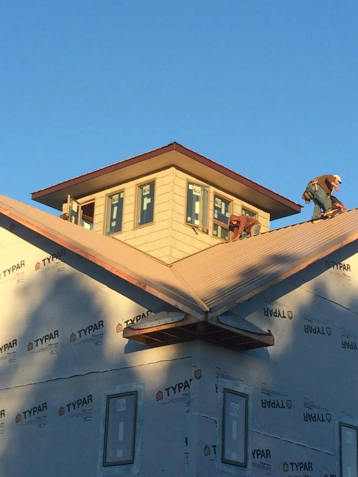 Roofers working around a rooftop cupola on a new metal roof at sunset — Roof Waterproofing in Oakland by Roofing Brothers